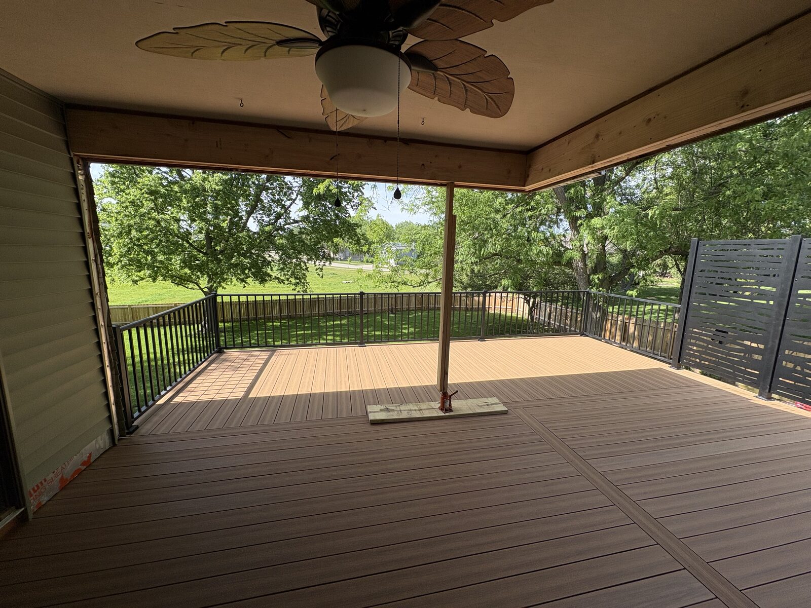 Interior view of covered deck with ceiling fan and green yard, Iowa City outdoor living