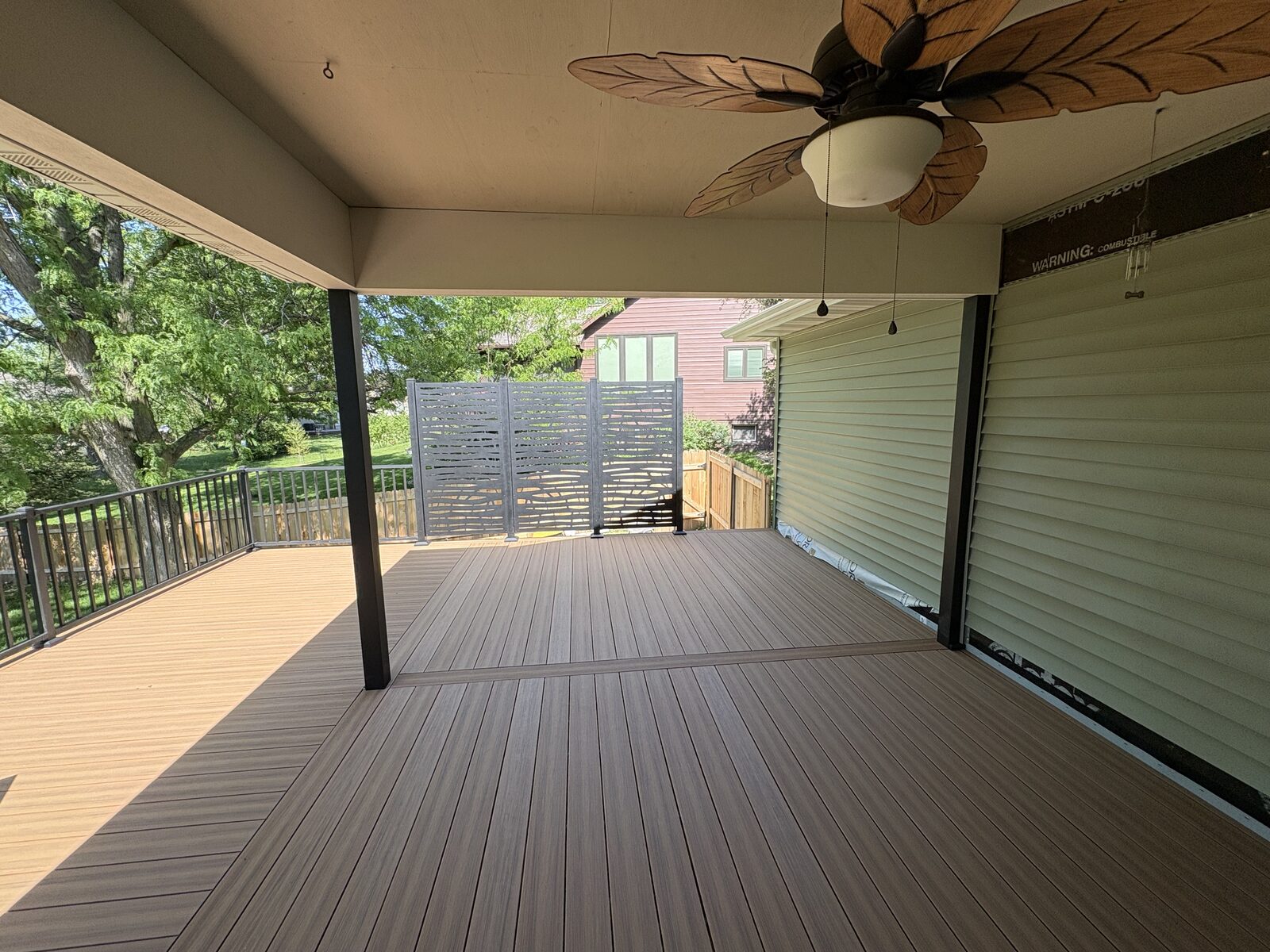 Covered deck overlooking backyard with decorative privacy panels, Iowa City deck builder