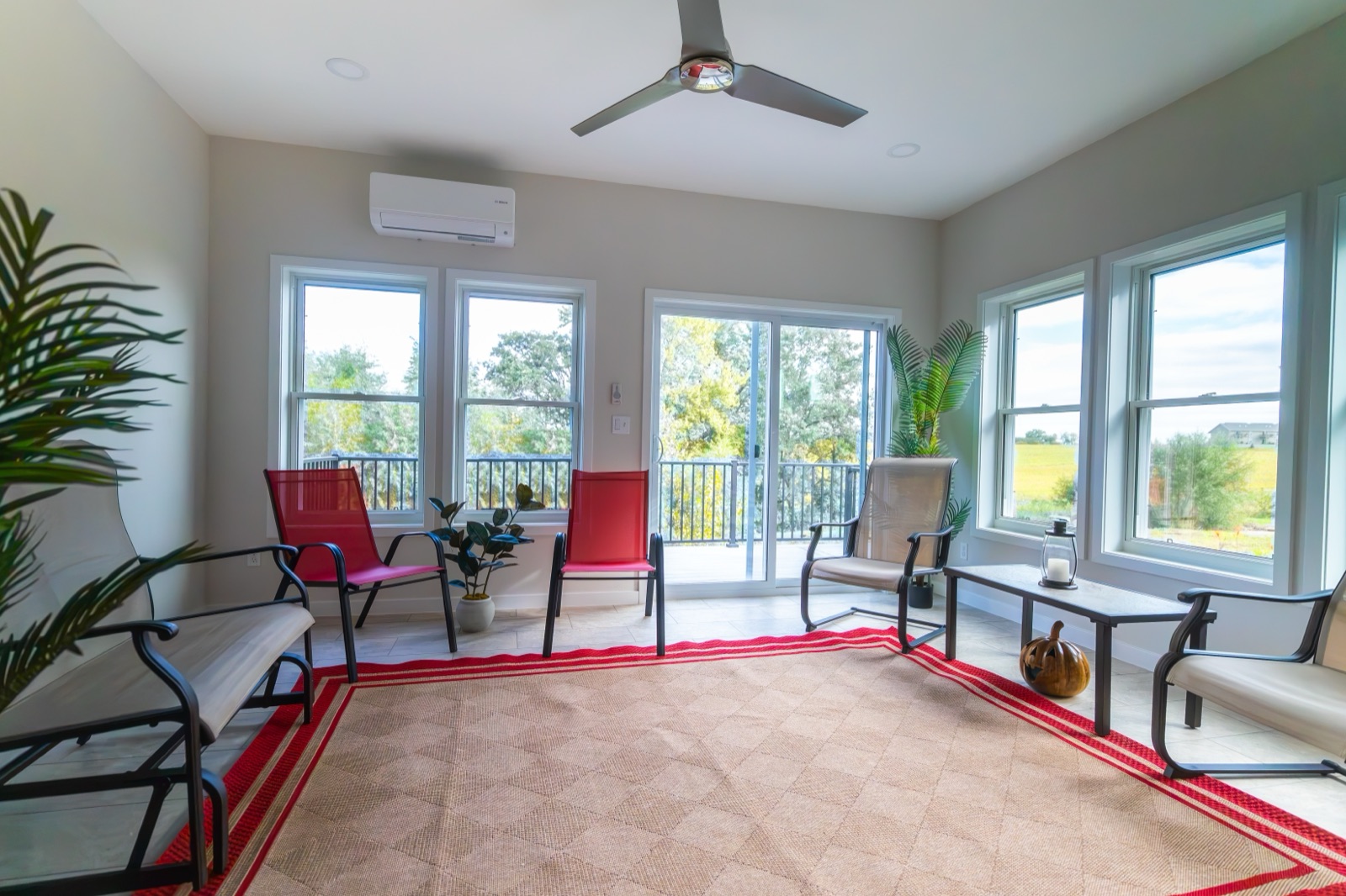 Four-season sunroom interior with mini-split, ceiling fan, and floor-to-ceiling windows in Iowa