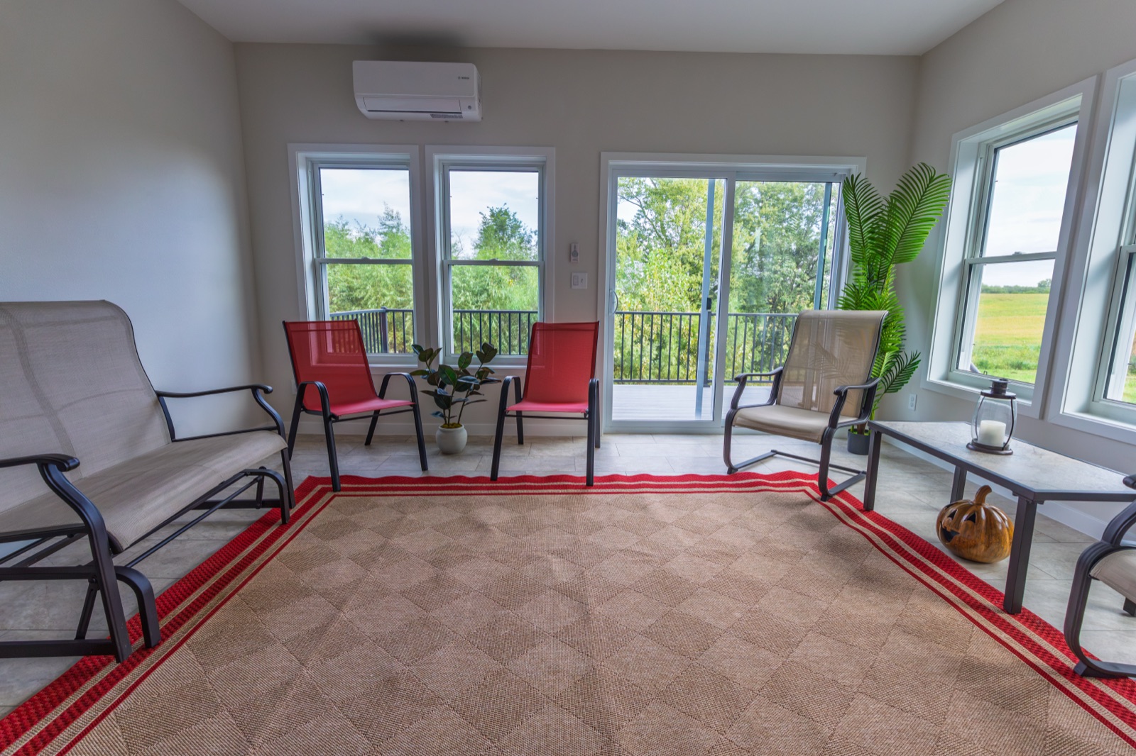Four-season sunroom interior with wall of windows and greenery view